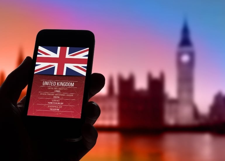 Hand holding mobile phone with UK flag and Big Ben in the background