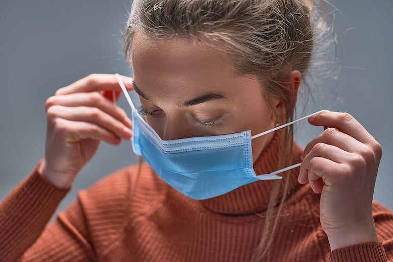 Woman putting on medical protective mask 