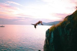 woman diving into sea from cliff