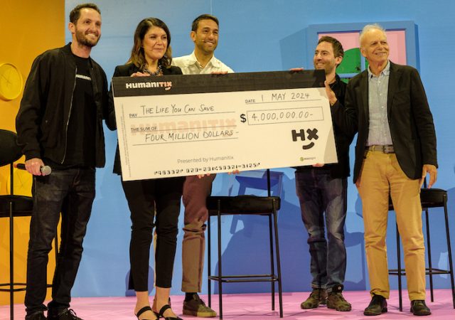 Humanitix cofounder Adam McCurdie presents The Life You Can Save director of philanthropy Louise Pfeiffer and co-CEO Andrea La Mesa with a $4 million donation, alongside his cofounder Josh Ross and ethicist and philosopher Peter Singer.